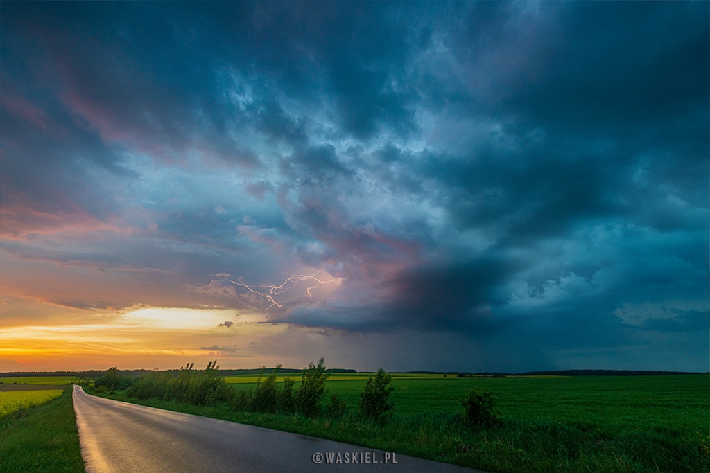 Fotografia burzy, która przedstawia światło i cień w pobliżu polnej drogi.
